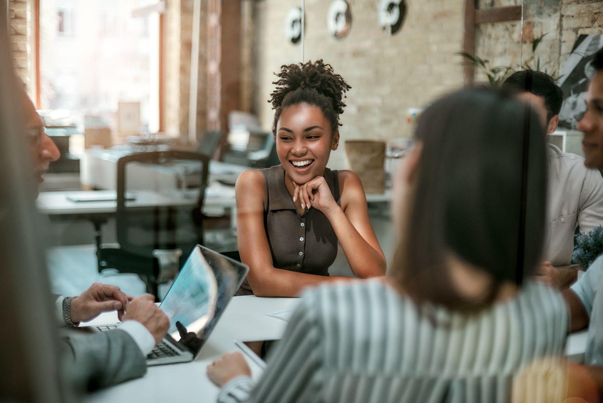 Young black woman smiles at her team around the table